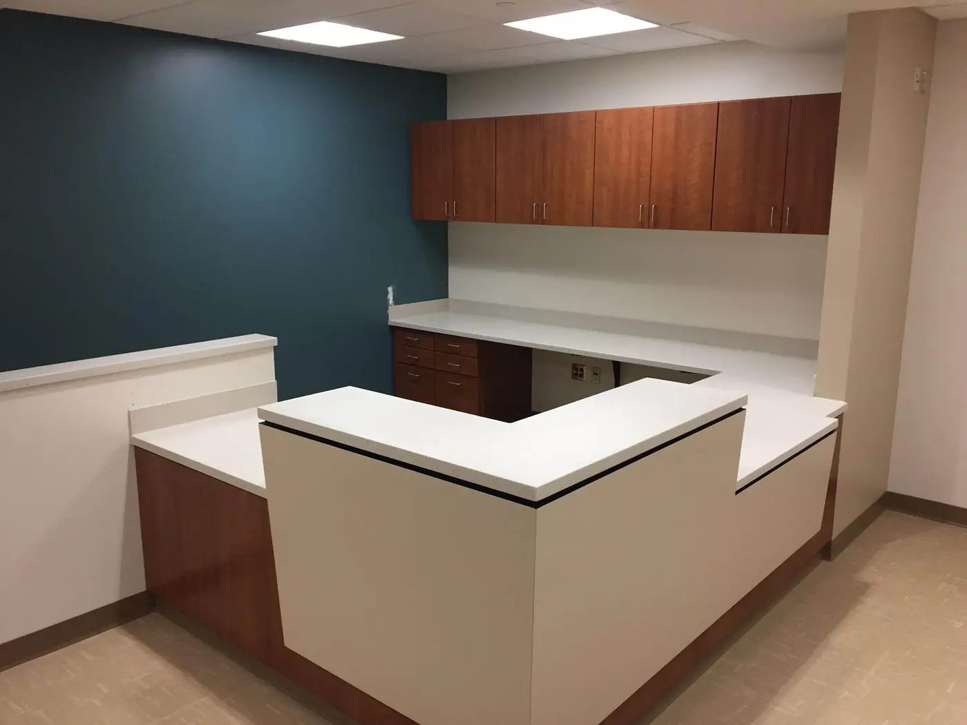 Medical office reception desk with white countertops and wood-tone upper cabinets