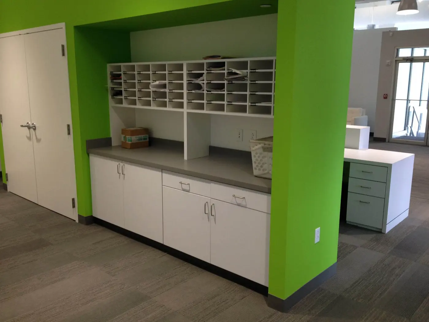 White office mailroom casework with sorting cubbies set into a lime green wall