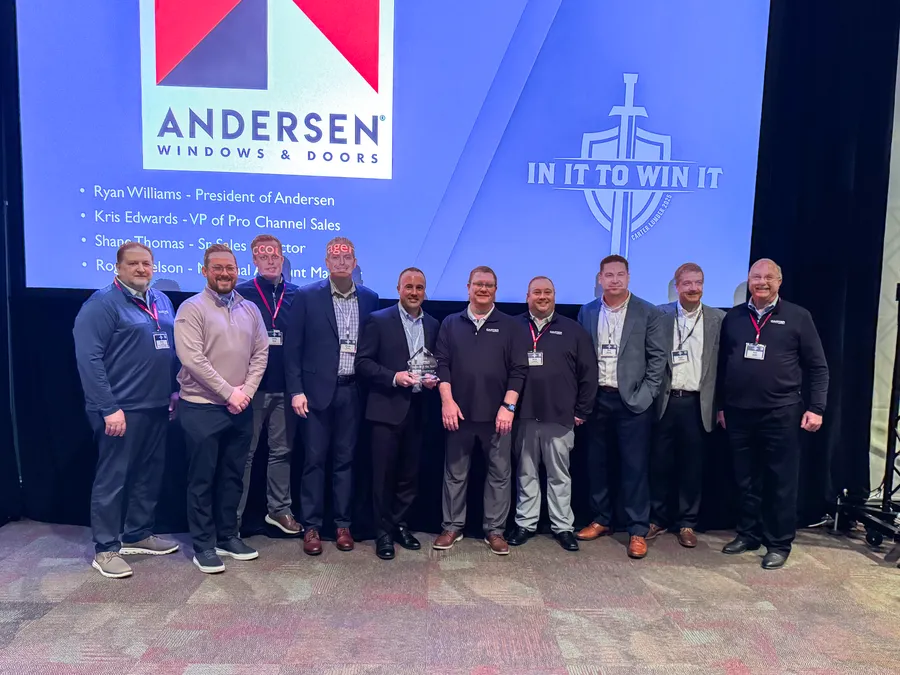 Carter Lumber and Andersen team members with an award in front of an Andersen Windows & Doors slide