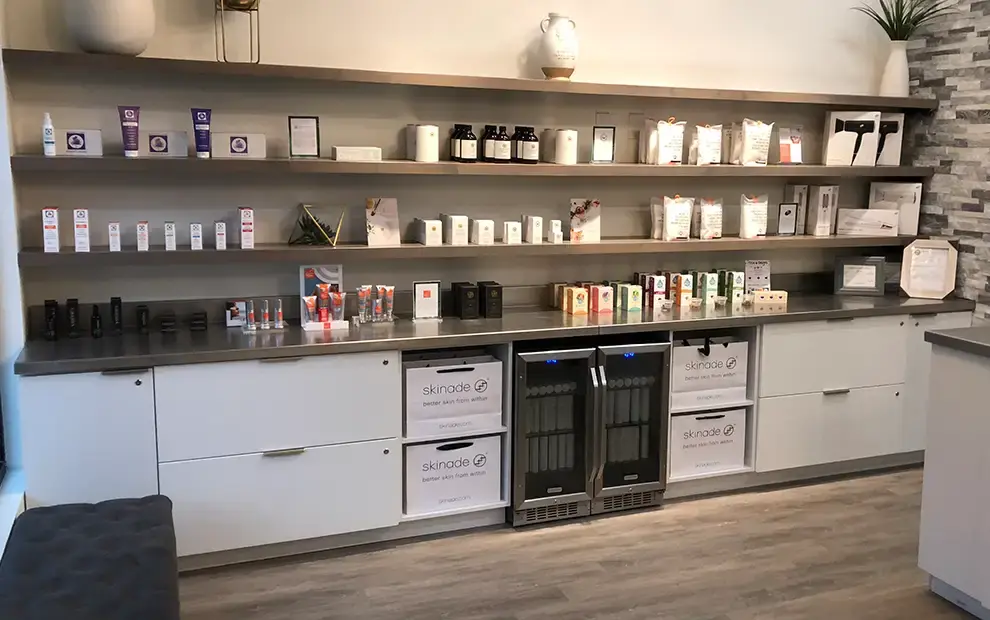 Retail wall of open shelves over white base cabinets with built-in beverage coolers