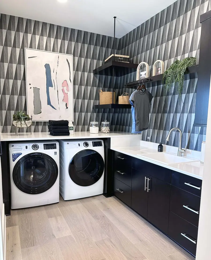 Laundry room with front-load washer and dryer, black cabinets and geometric wallpaper