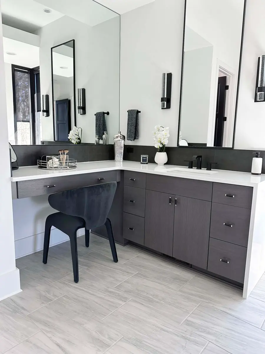 Bathroom vanity with dark wood cabinets, white countertop, makeup desk and black chair