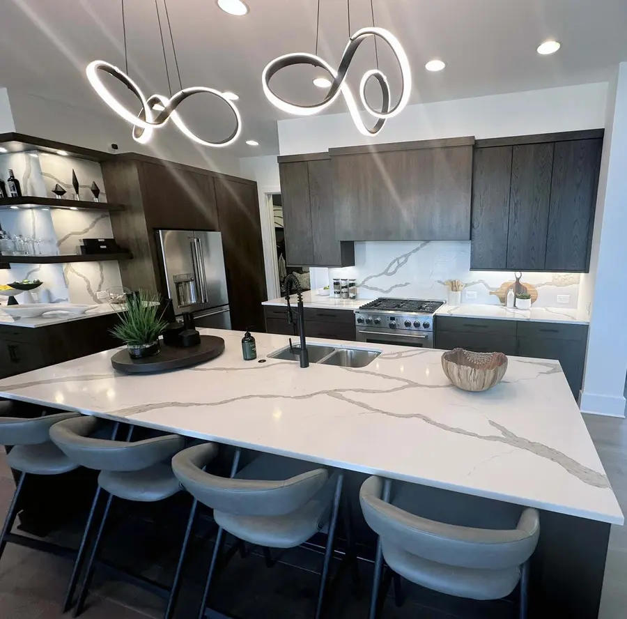 Marble-look island with seating facing dark wood cabinets and stainless range