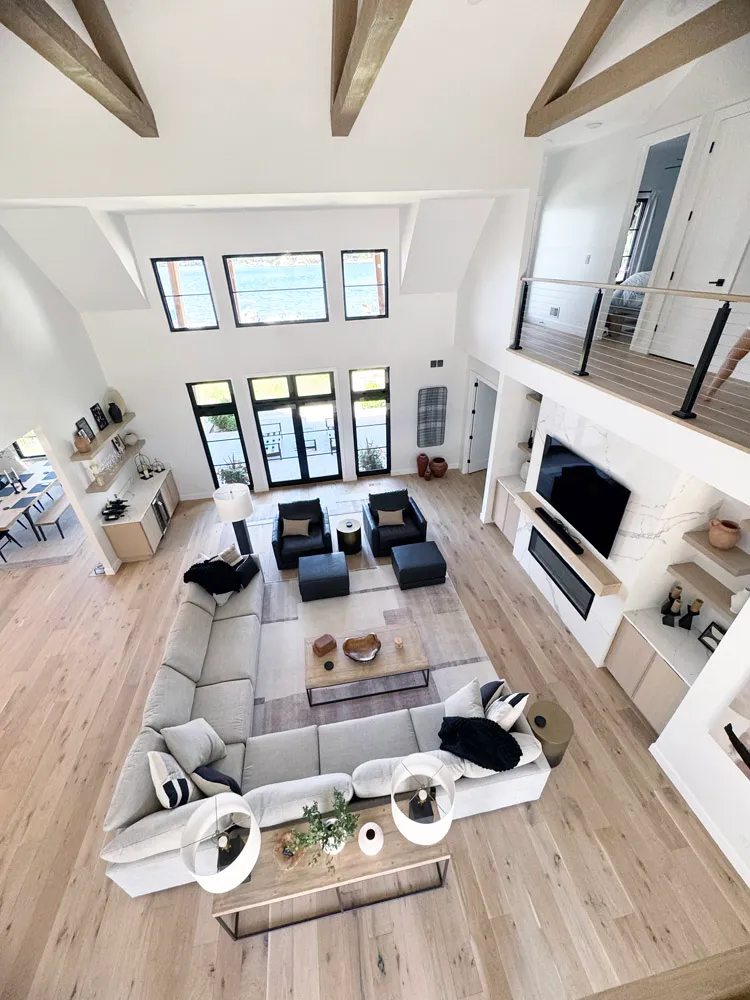 Overhead view of a vaulted great room with sectional, fireplace wall and tall windows