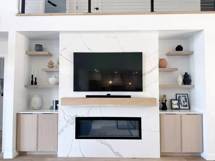 Marble-look fireplace wall with TV, wood mantel and light wood built-in cabinets