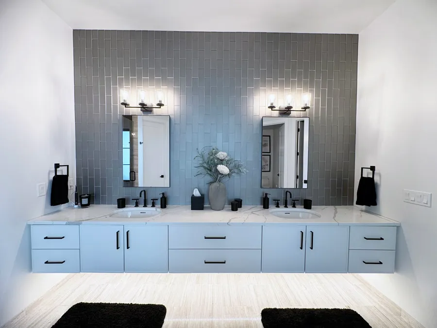 Floating double vanity in light blue-gray with marble-look top and gray tile wall