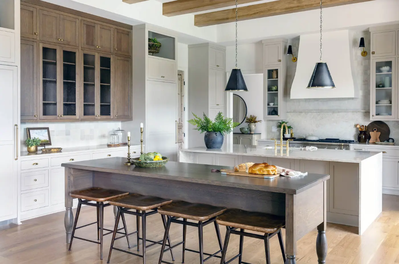 Kitchen with dark wood-topped island, wood bar stools and white range hood