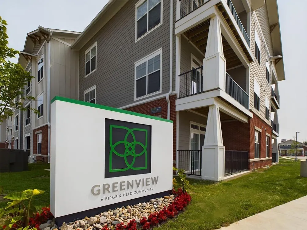 Greenview apartment building with balconies behind a sign reading Greenview, a Birge & Held community