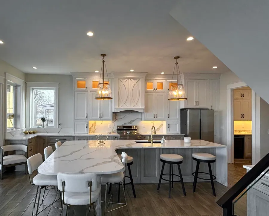 White kitchen with curved marble-look island, gray island base and lantern pendants