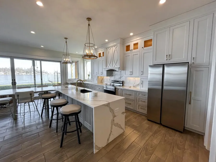 Kitchen with waterfall island, stainless refrigerator and sliding doors to a lake view
