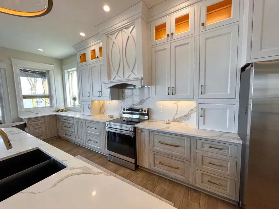 Gray-washed and white cabinets with marble-look backsplash around a stainless range