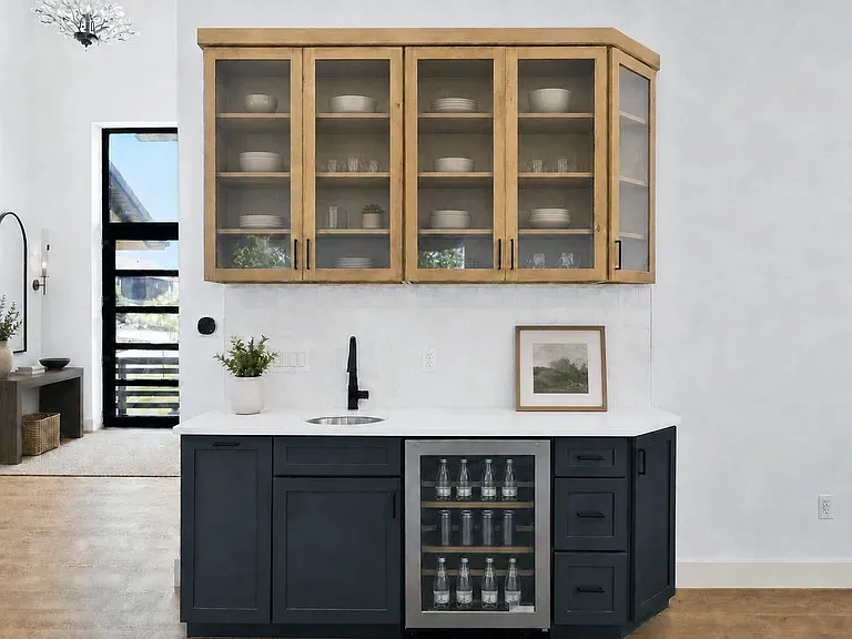 Wet bar with wood glass-front upper cabinets above charcoal base and beverage fridge
