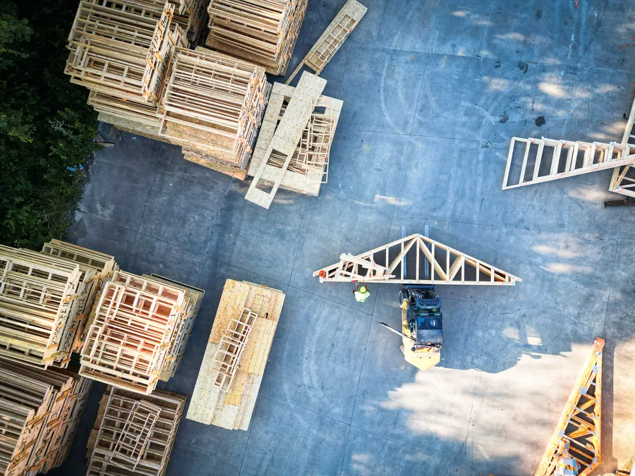 Overhead view of a forklift carrying a roof truss through a truss yard