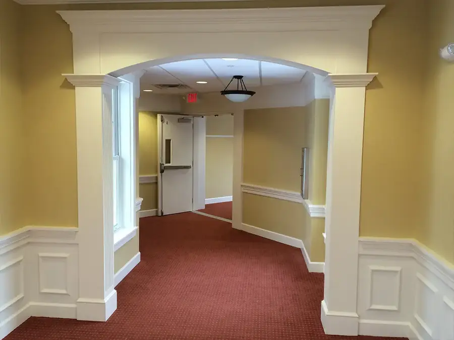 Arched trim opening with fluted pilasters and wainscot panels in a hallway