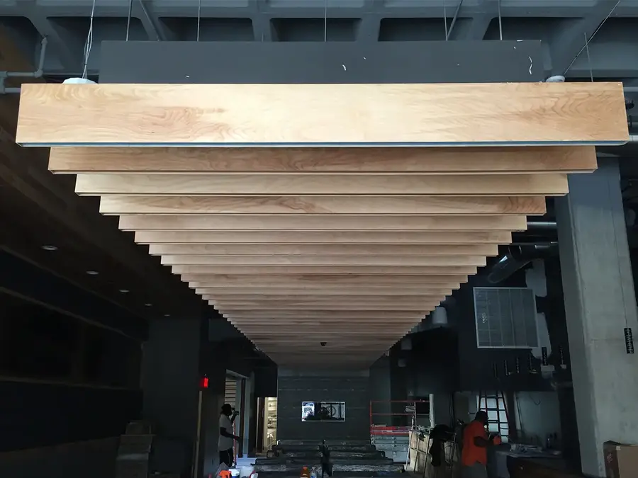Suspended wood-look ceiling baffles stepping down a commercial space under construction