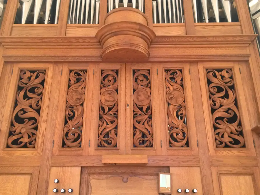 Carved wood organ case with ornate scrollwork panels below organ pipes