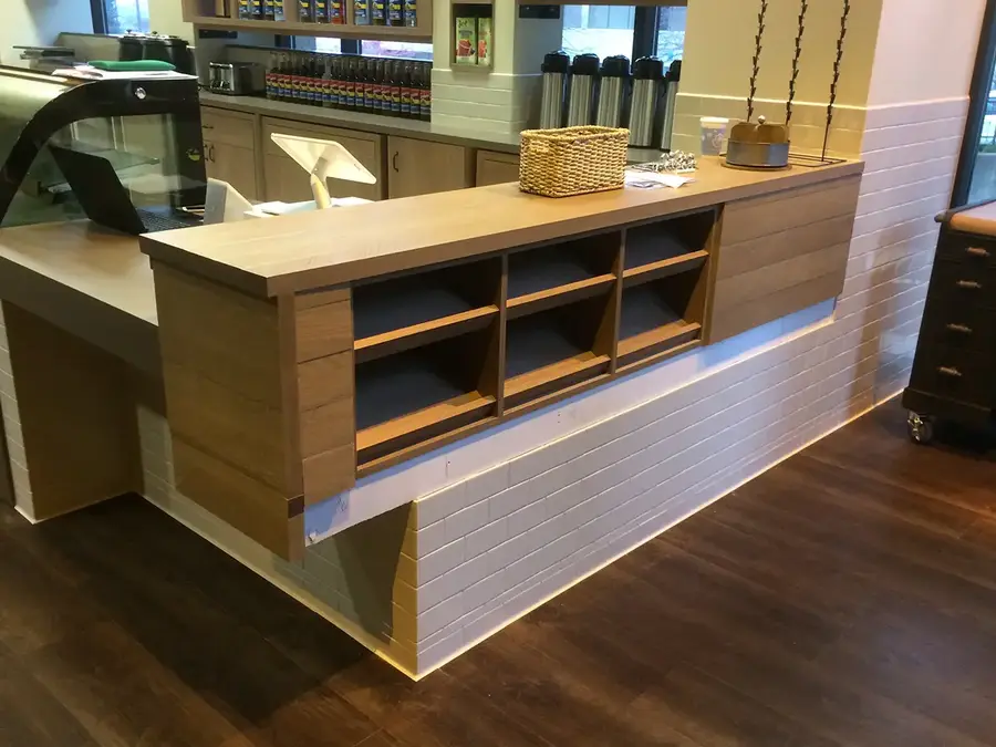 Coffee shop service counter with wood-grain casework and open cubbies