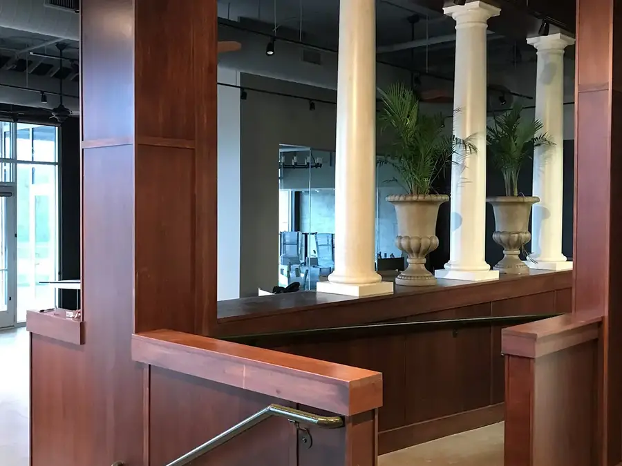 Restaurant entry with wood-paneled half walls, white columns and potted palms