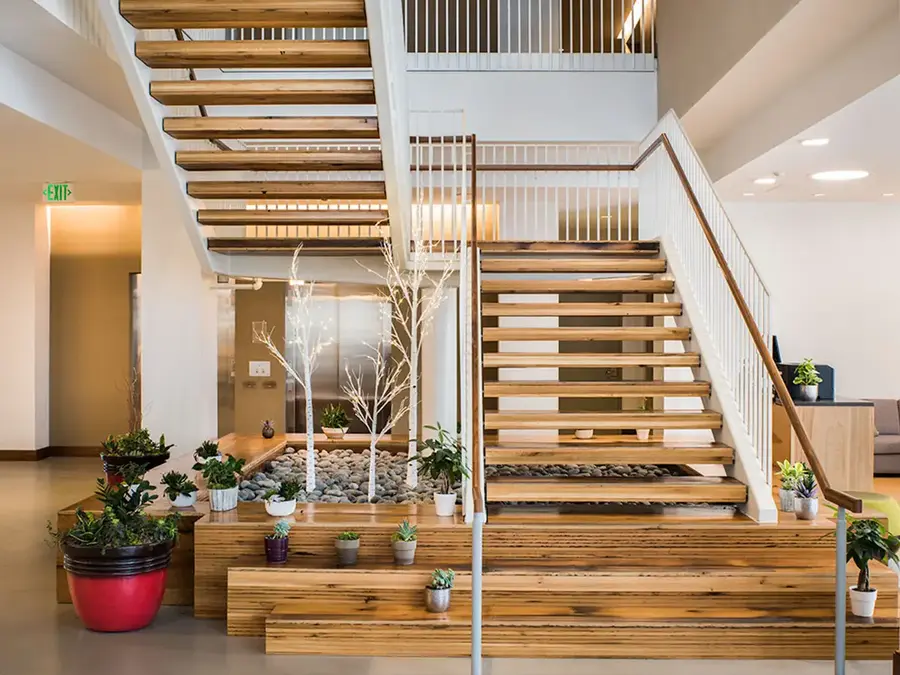 Open wood staircase over tiered wood planters in a bright commercial lobby