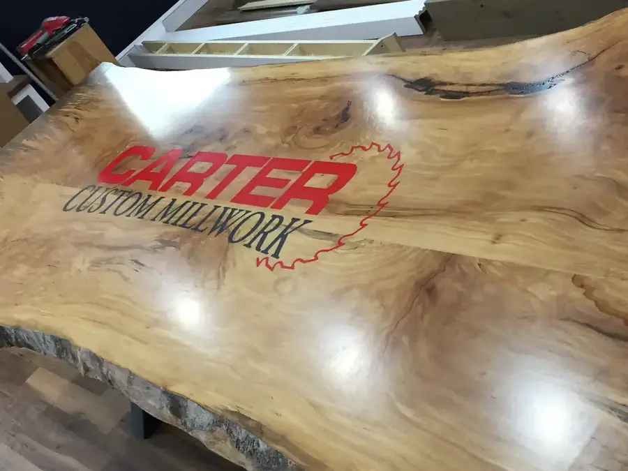 Live-edge slab table inlaid with the Carter Custom Millwork logo