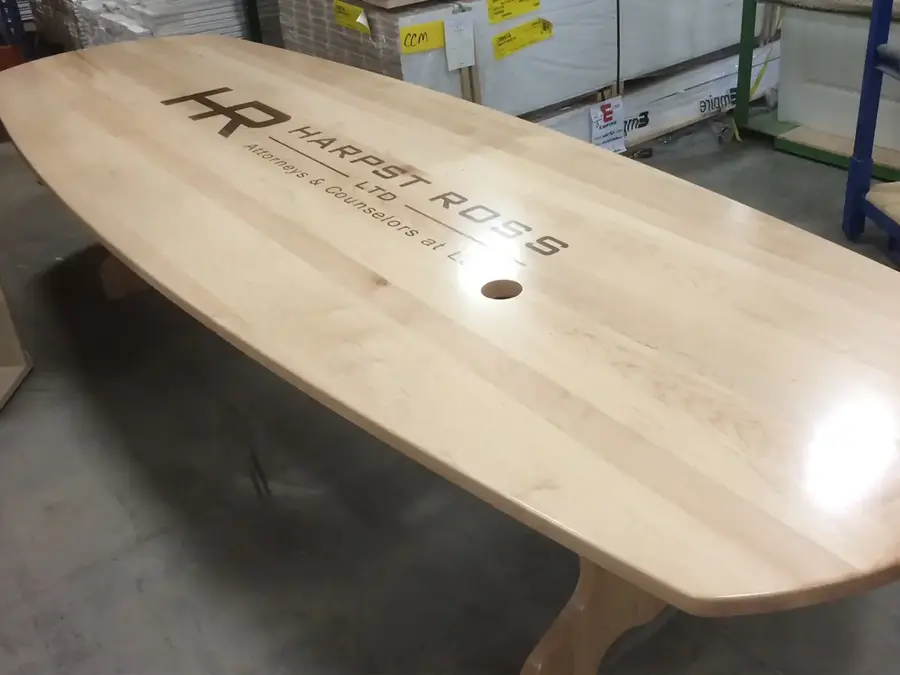 Light wood conference table engraved with the Harpst Ross law firm logo