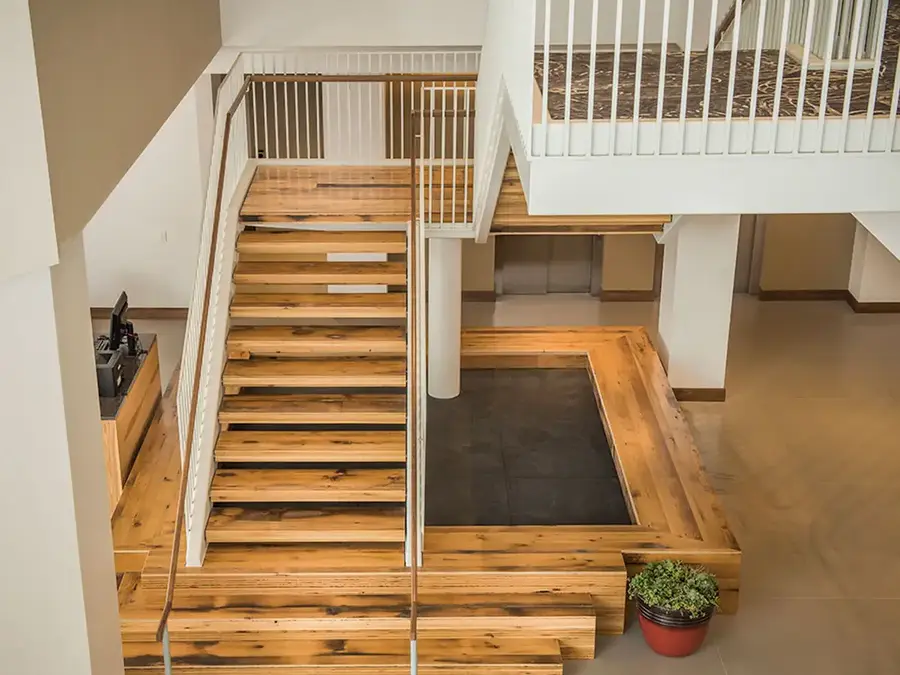 Open wood staircase over a tiered wood platform in a commercial lobby, seen from above
