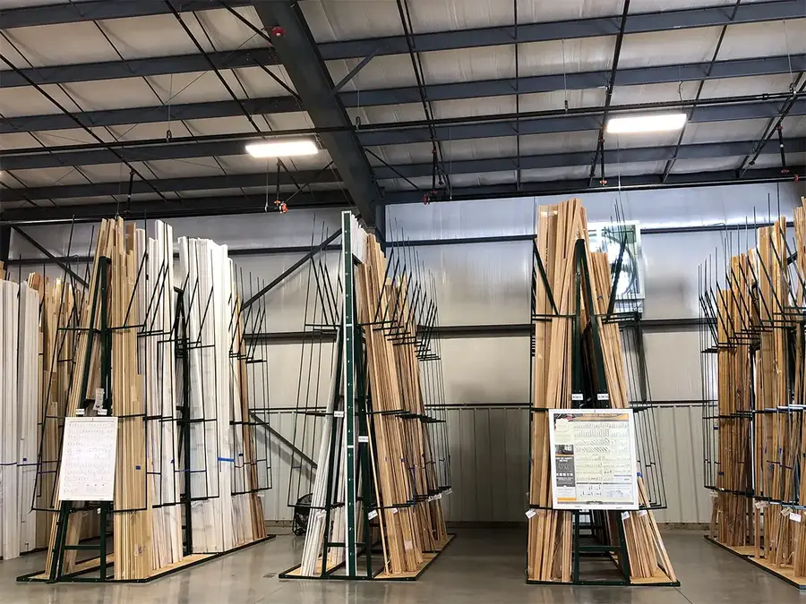 Trim boards stored upright in green A-frame racks in a warehouse