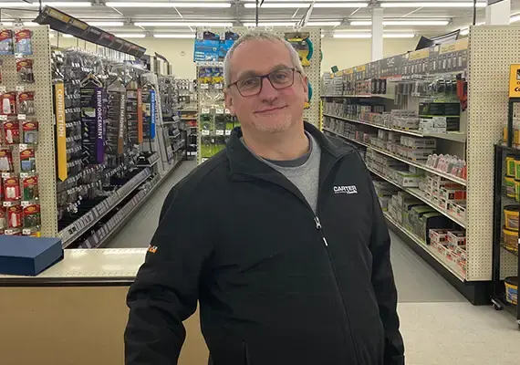 Smiling Carter store employee standing in a hardware aisle