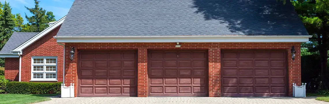 Brick three-car garage with dark red raised-panel doors