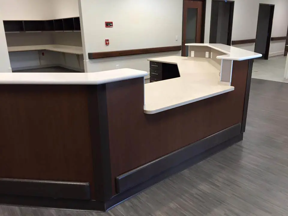 Dark wood-grain reception desk with white counters in an institutional lobby