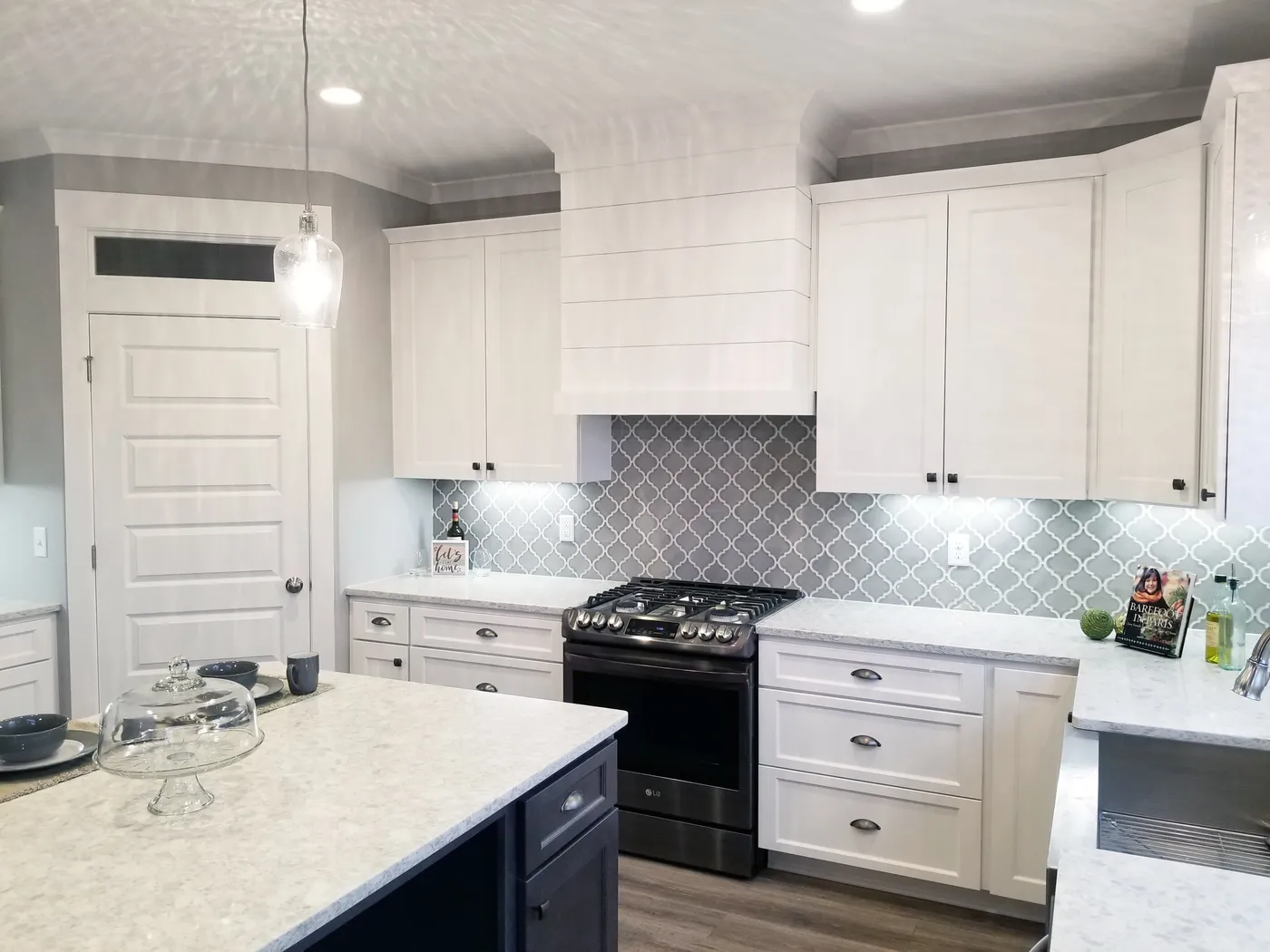 White shaker cabinets and shiplap range hood over gray arabesque tile backsplash