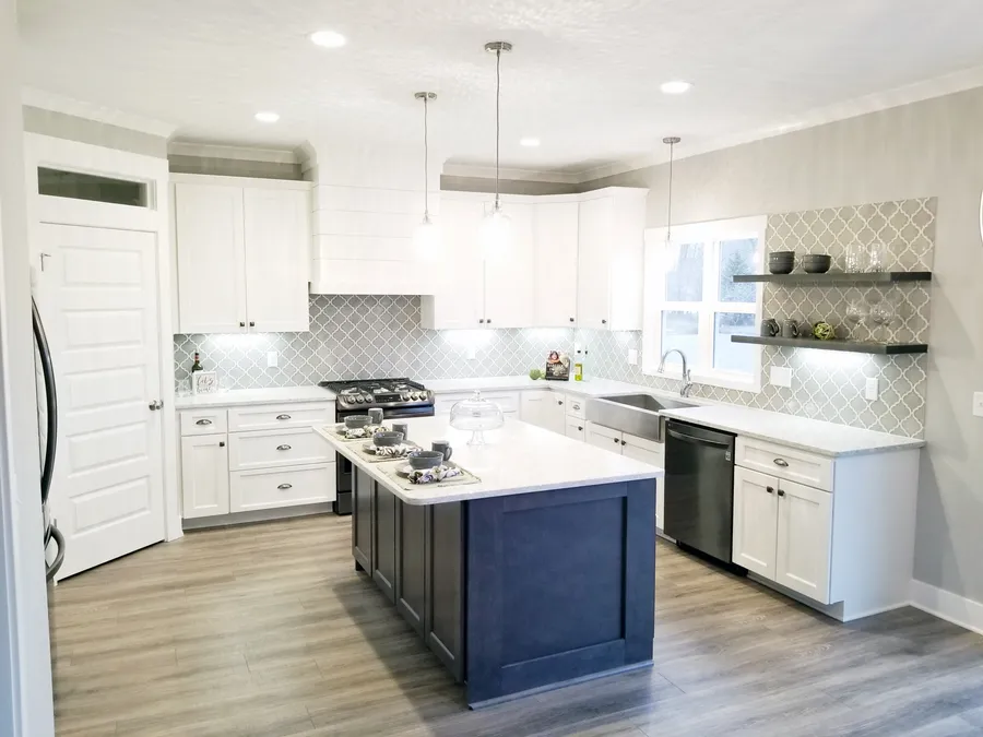 White kitchen with navy island, gray arabesque tile and floating shelves