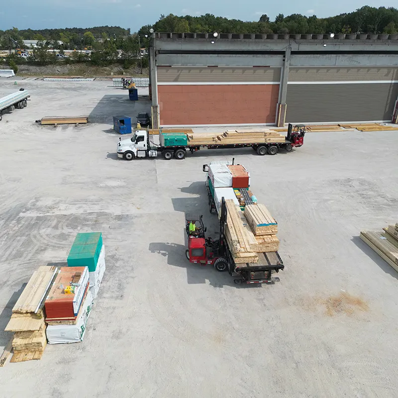 Forklift loading lumber onto a flatbed truck in a lumber yard