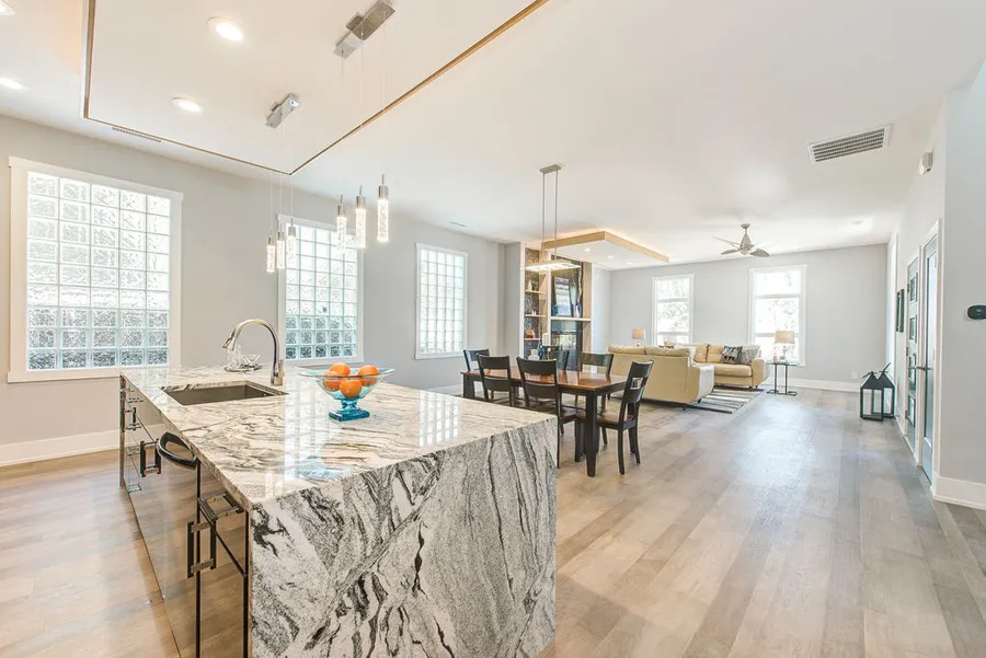 Marble waterfall island with crystal pendants opening to dining and living areas