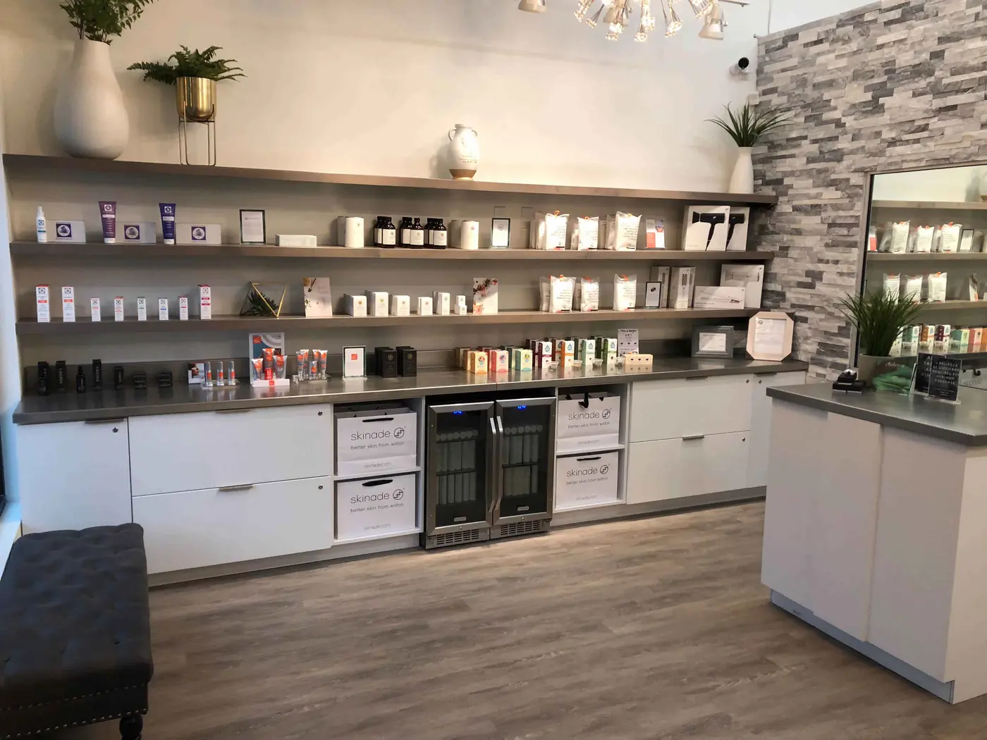 Retail wall of floating shelves over white base cabinets with built-in beverage coolers