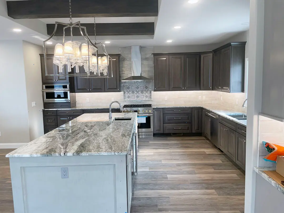 Dark gray kitchen with granite island, chimney range hood and patterned tile accent