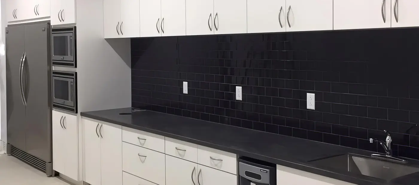Commercial kitchen with white cabinets, black subway tile backsplash and dark countertop