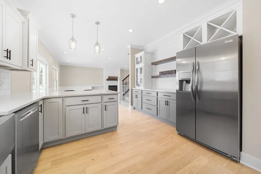 Gray and white kitchen with stone peninsula, glass pendants and stainless refrigerator