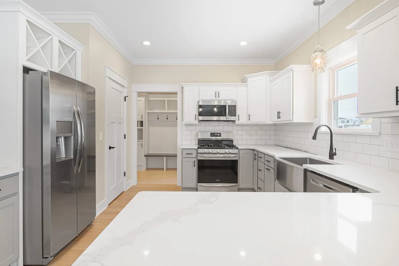 White and gray kitchen seen across a stone peninsula toward a mudroom