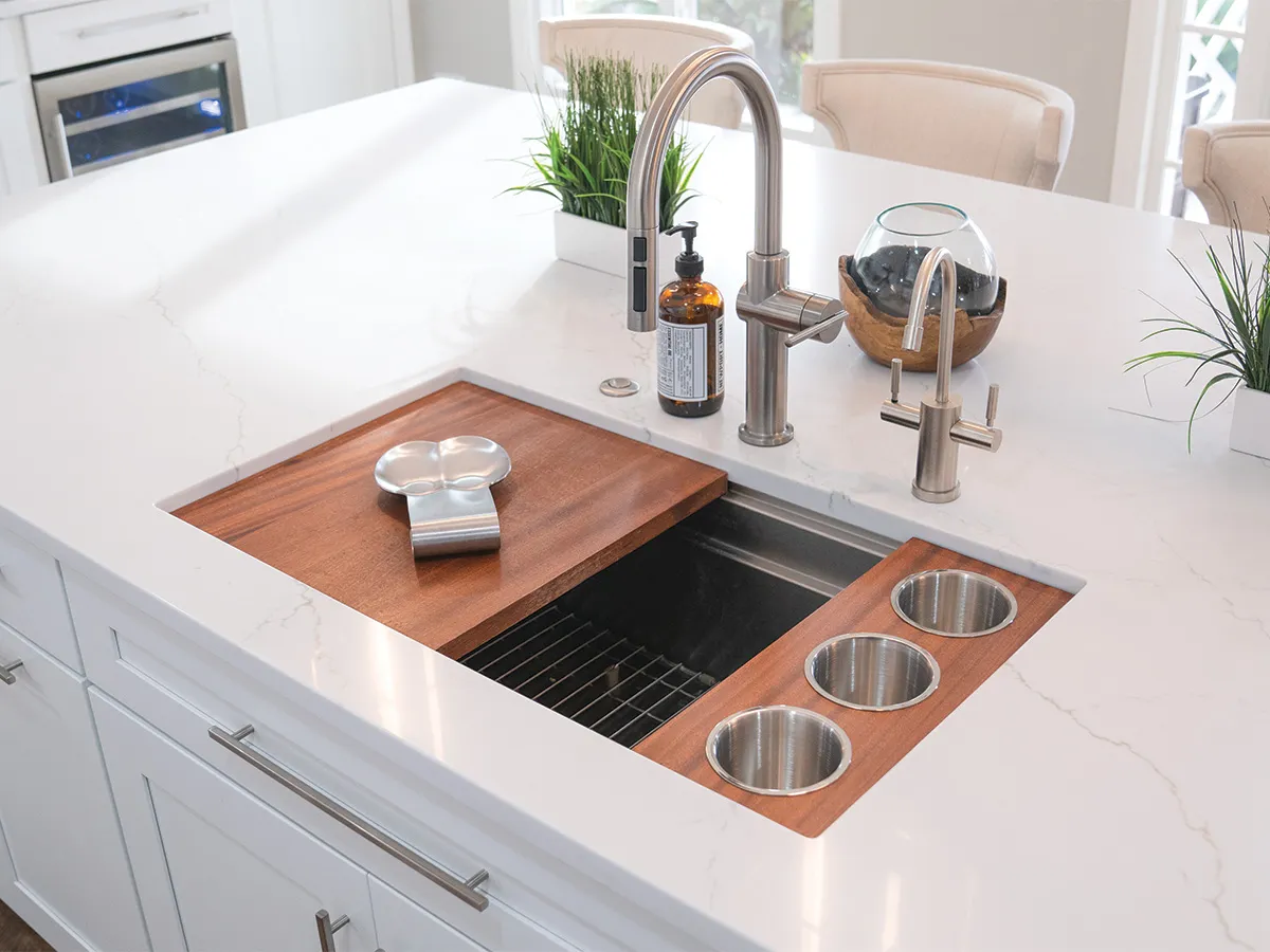 Island workstation sink with wood cutting board, stainless cups and brushed faucets