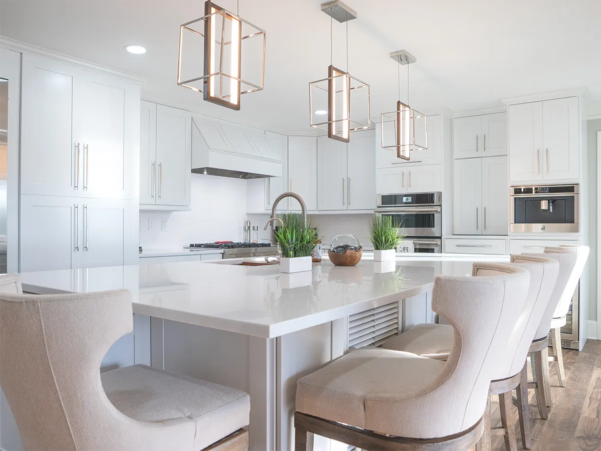 White kitchen with large island, upholstered bar stools and cube pendant lights