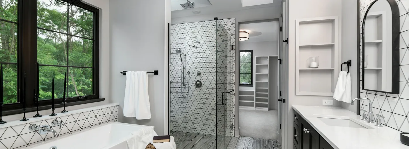 Bathroom with soaking tub, glass walk-in shower with geometric tile and black-framed windows