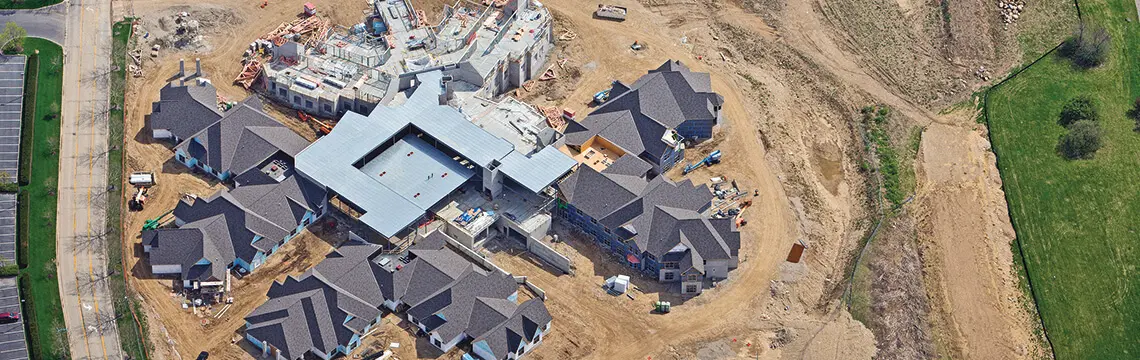 Aerial view of a large building under construction with several roofed wings