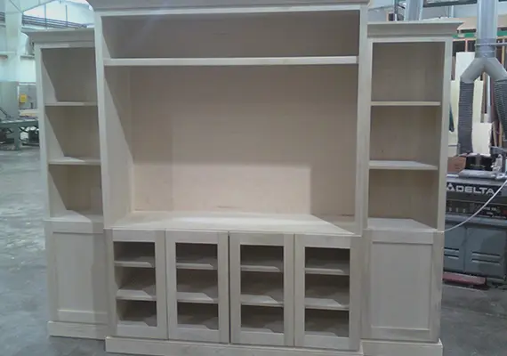Unfinished custom entertainment center with open shelves in a millwork shop