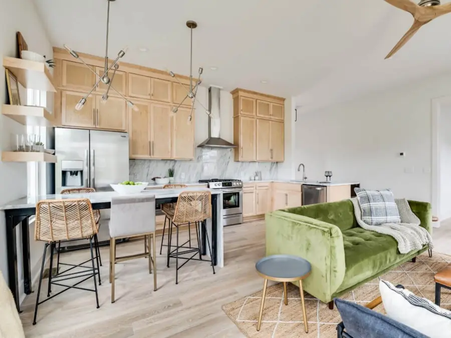 Open kitchen and living room with light wood cabinets and a marble-top island