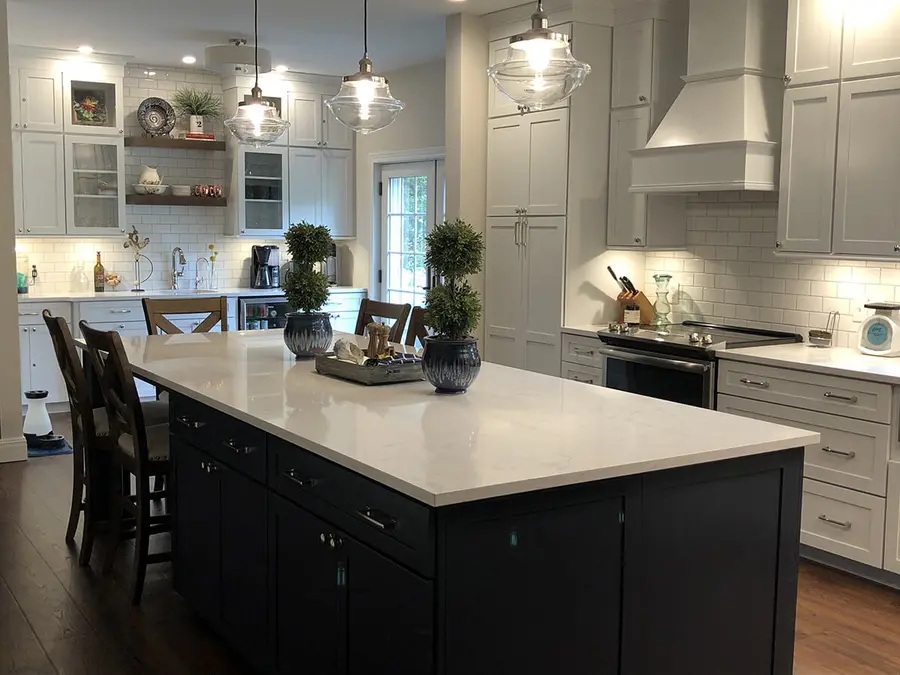 White kitchen with dark navy island, white stone top and subway tile backsplash