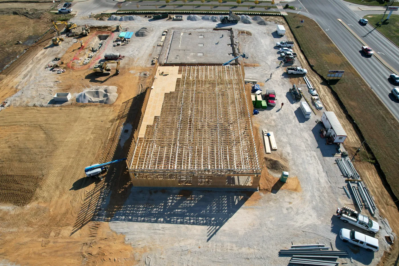 Aerial view of a commercial building under construction with roof trusses installed
