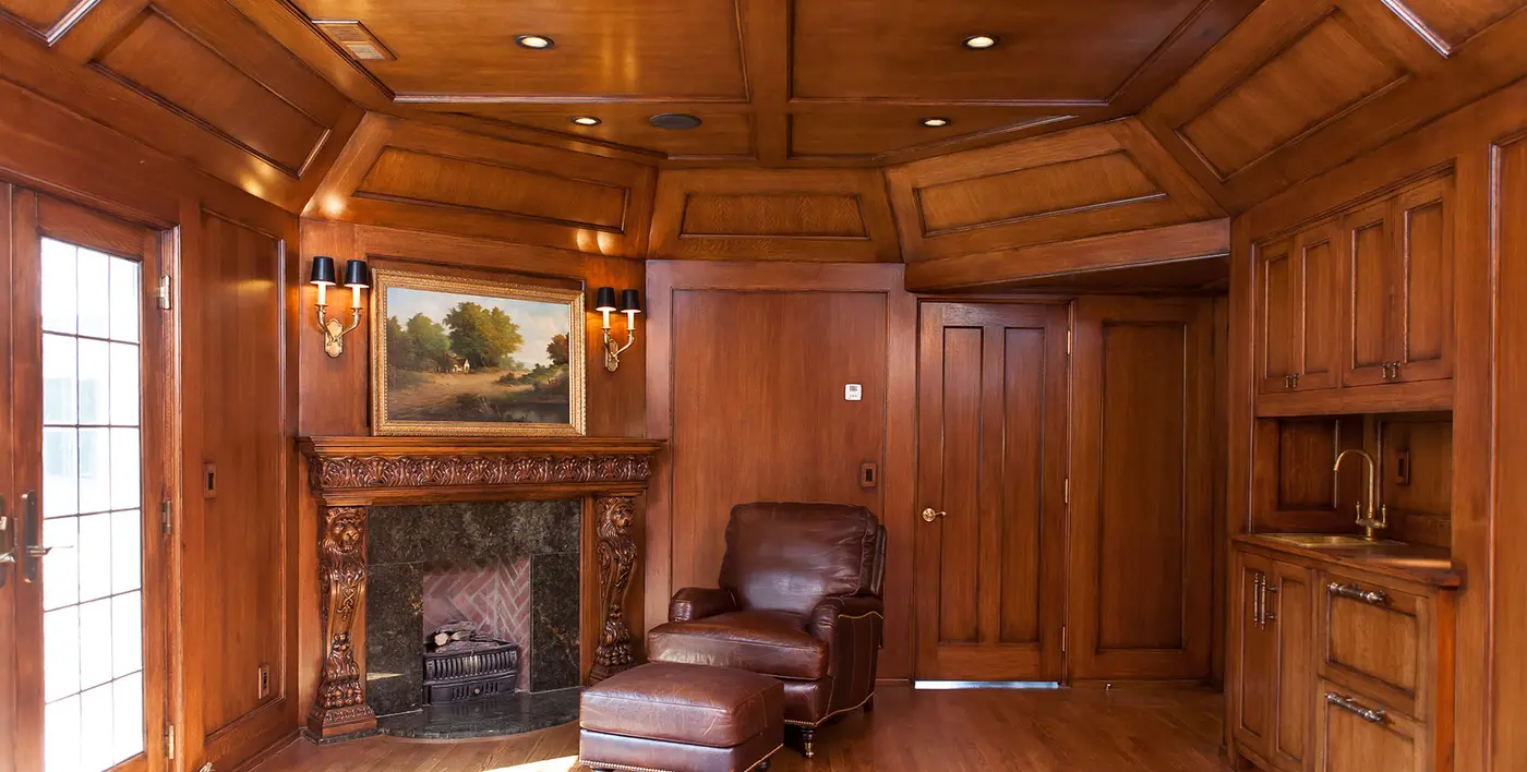 Wood-paneled study with coffered ceiling, carved fireplace and leather armchair