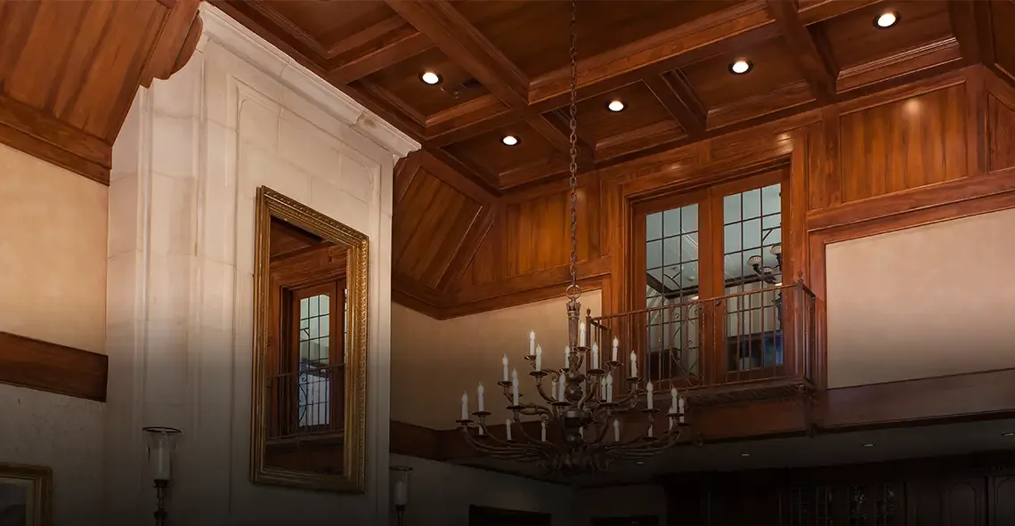 Grand room with wood-paneled coffered ceiling, balcony and candle chandelier