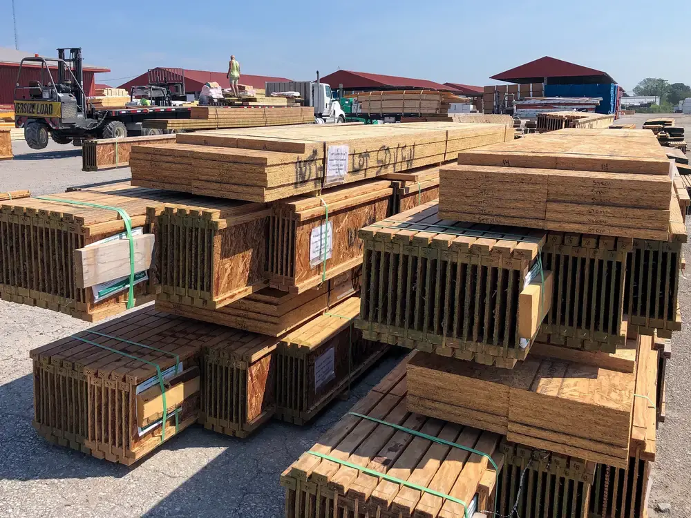 Strapped bundles of wood I-joists stacked in an outdoor lumber yard